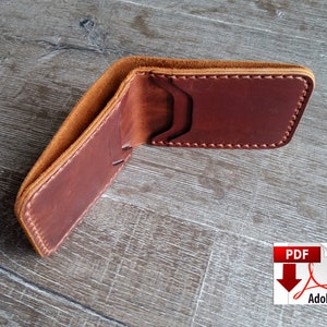 May include: Open brown leather wallet with visible stitching and card slots. The wallet is made of a rich, reddish-brown leather with a lighter tan interior. The wallet is open, displaying its interior design.