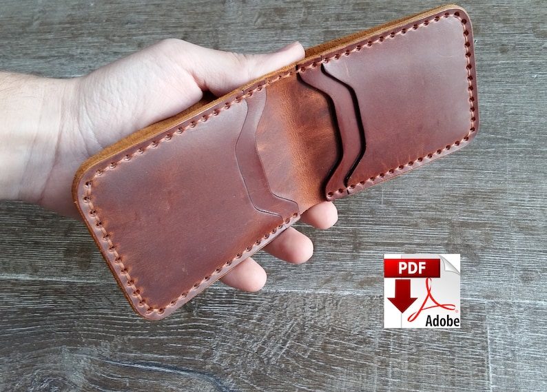 May include: Open, handmade brown leather wallet with visible stitching. The wallet has multiple card slots and a bill compartment. The edges are a lighter brown color. The wallet is held open, showcasing its interior.