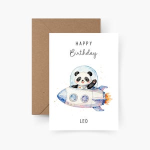 Puede incluir: Tarjeta de cumpleaños blanca con una ilustración de acuarela de un panda en un cohete. La tarjeta dice "HAPPY Birthday" y "LEO". El cohete es blanco y azul con llamas naranjas.