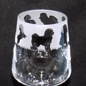 May include: A clear glass wine glass with a frosted design of black silhouettes of dogs. The glass has a long stem and a round base.