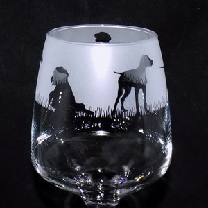 May include: A frosted glass wine glass with a silhouette of three dogs etched on the side. The dogs are black and the glass is clear.