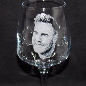 May include: A clear glass wine glass with an etched image of a man's face.