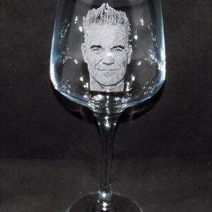 May include: A clear glass wine glass with an etched image of a man's face.