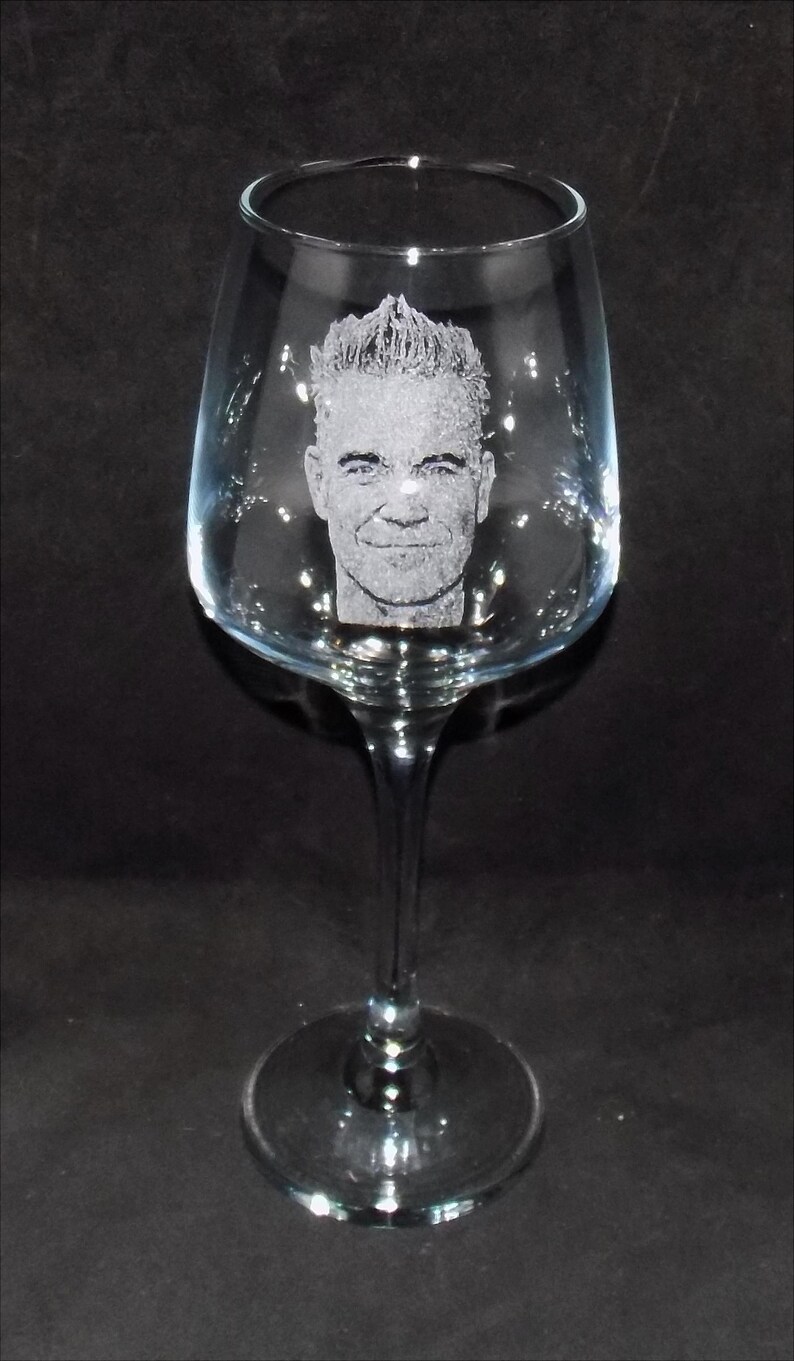 May include: A clear glass wine glass with an etched image of a man's face.