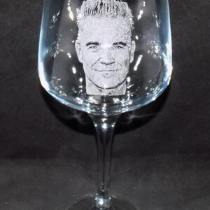 May include: A clear glass wine glass with a personalized etched design of a man's face.