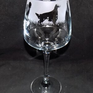May include: A clear glass wine glass with a frosted design of a dog and other animals. The design is etched into the glass.