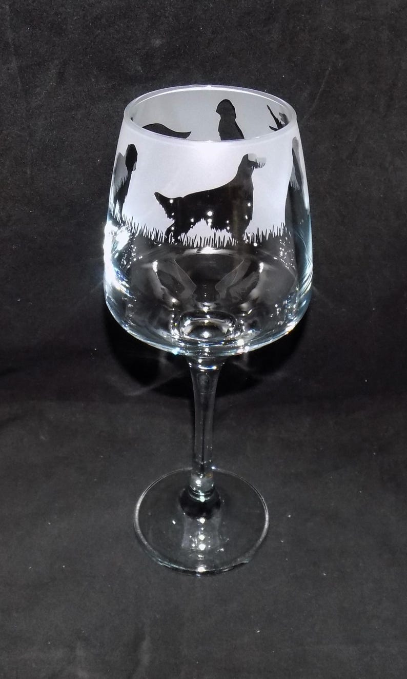 May include: A clear glass wine glass with a frosted design of a dog and other animals. The design is etched into the glass.