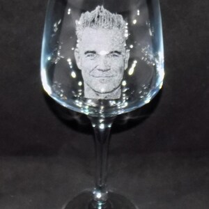 May include: A clear glass wine glass with a personalized etched image of a man's face.