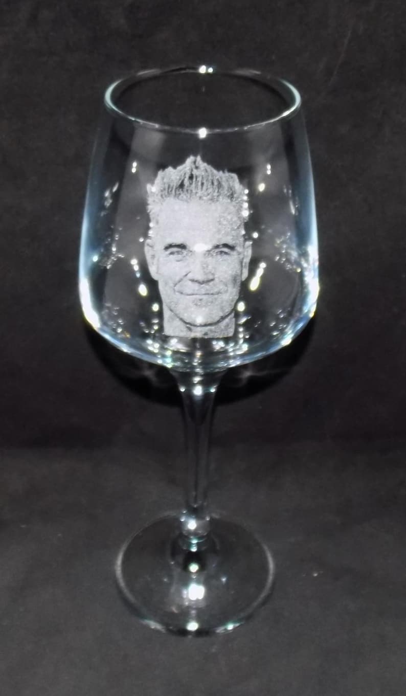 May include: A clear glass wine glass with a personalized etched image of a man's face.