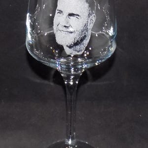 May include: A clear glass wine glass with a personalized etched design of a man's face.