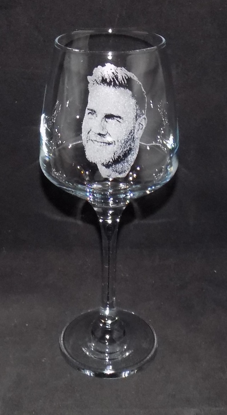 May include: A clear glass wine glass with a personalized etched design of a man's face.