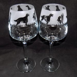May include: Two clear glass wine glasses with etched silhouettes of dogs. The glasses have a frosted finish and are perfect for any dog lover.