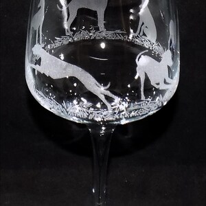 K&ouml;nnte beinhalten: Ein Weinglas aus klarem Glas mit ge&auml;tzten wei&szlig;en Silhouetten von Windhunden in verschiedenen Posen, darunter stehend, sitzend und rennend, die in einem kreisf&ouml;rmigen Muster um den Kelch &uuml;ber einem schlanken Stiel und Fu&szlig; angeordnet sind.