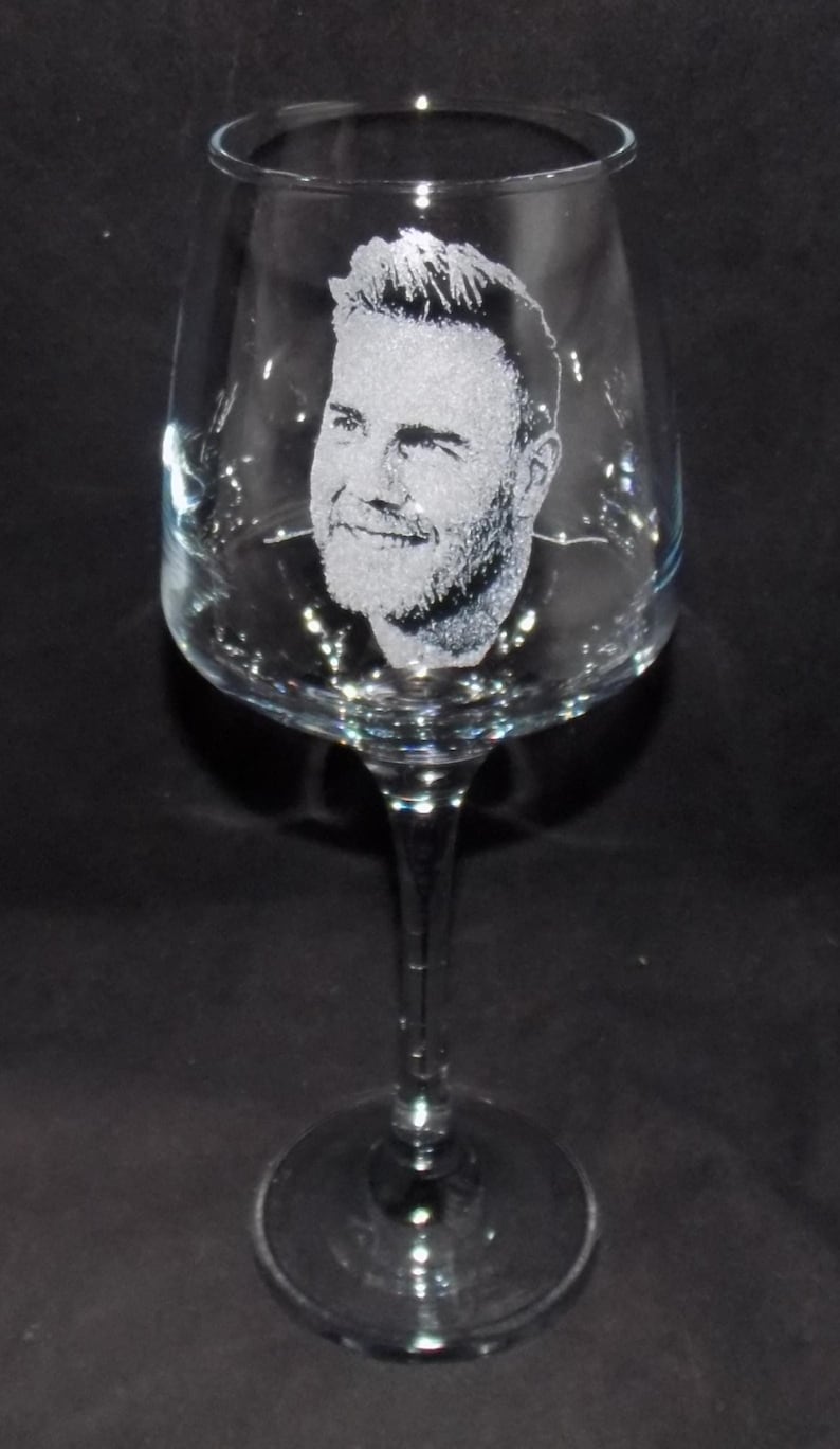 May include: A clear glass wine glass with an etched image of a man's face.