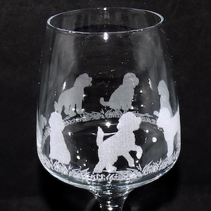 May include: A clear glass wine glass with an etched design of five dogs in a circle. The dogs are all different breeds and are facing inwards towards the centre of the circle.