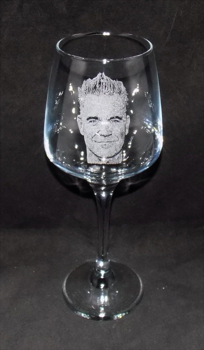 May include: A clear glass wine glass with a personalized etched image of a man's face.