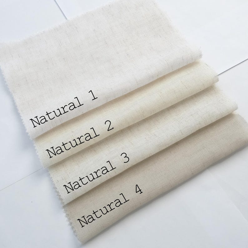 Pu&ograve; includere: Quattro campioni di tessuto rettangolari disposti in una pila, ognuno con una tonalit&agrave; distinta di bianco sporco o beige. I campioni sono etichettati con testo nero come Natural 1, Natural 2, Natural 3 e Natural 4, mostrando una trama tessuta.