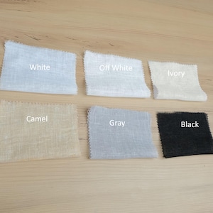 Pu&ograve; includere: Sei campioni di tessuto rettangolari disposti su due file. La fila superiore include White, Off White e Ivory. La fila inferiore include Camel, Gray e Black. Ogni campione presenta una trama visibile e bordi dentellati con etichette stampate.