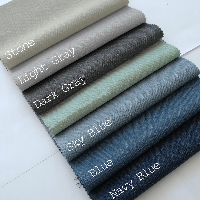 May include: A collection of fabric swatches arranged in a diagonal stack, featuring the colors Stone, Light Gray, Dark Gray, Sky Blue, Blue, and Navy Blue. Each swatch displays a woven texture and is labeled with its corresponding color name in white text.