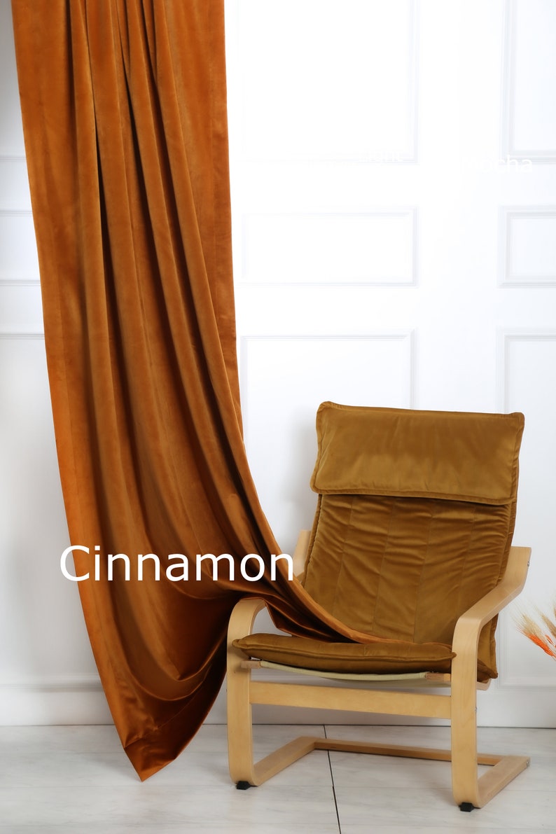 May include: Cinnamon-colored velvet curtain draped next to a matching chair. The chair has a wooden frame and a cushioned seat and back. The word "Cinnamon" is displayed on the curtain.