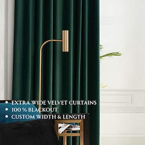 May include: Dark green velvet curtains with vertical folds. The curtains are extra wide and 100% blackout. The text on the image says "EXTRA WIDE VELVET CURTAINS", "100 % BLACKOUT", and "CUSTOM WIDTH & LENGTH". A gold-colored lamp is in the foreground.