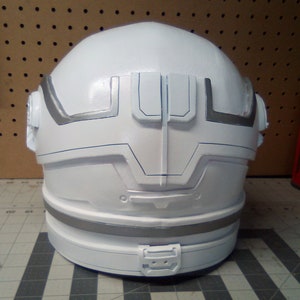 May include: White helmet with silver accents and a black stripe around the bottom. The helmet has a unique design with a raised section on the back.