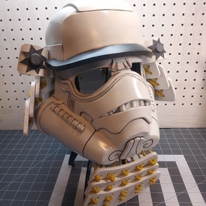 May include: A white and black samurai helmet with yellow accents. The helmet is made of a hard material and has a detailed design.