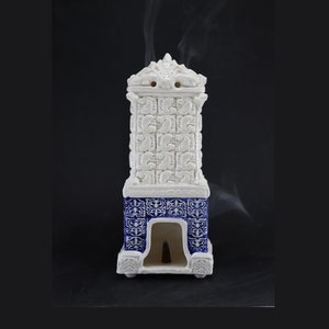 May include: White ceramic incense burner with blue and white patterned base. Smoke rises from the top of the burner.