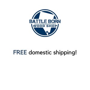 Pode incluir: Fundo branco com um logotipo circular azul marinho que diz "BATTLE BORN WOOD SHOP". Abaixo do logotipo, o texto "FREE domestic shipping!" &eacute; exibido em azul marinho.
