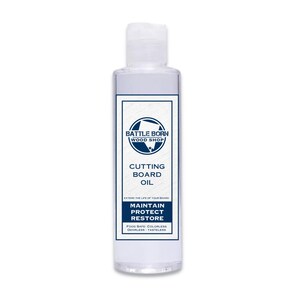 Pu&ograve; includere: Una bottiglia trasparente di olio per taglieri di Battle Born Wood Shop. L'etichetta presenta un design blu e bianco con le parole "Cutting Board Oil", "Maintain, Protect, Restore" e "Food Safe". La bottiglia &egrave; alta circa 13 cm.