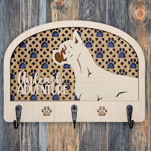 May include: Wooden key holder with a dog silhouette and paw print designs. The key holder has three hooks and the text "Unleash Adventure".