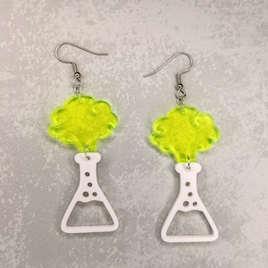 May include: A pair of earrings featuring a white beaker with a yellow cloud on top. The earrings are made of acrylic and have silver hooks.