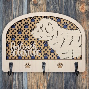 May include: Wooden key holder with a cutout design of a dog and paw prints. The key holder has three hooks and the text "Unleash Adventure" is printed on the front.