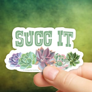Puede incluir: Una pegatina blanca con el texto "SUCC IT" en letras verdes, sobre una fila de ilustraciones de suculentas coloridas. Las suculentas son en tonos morados, verdes y rosas. La pegatina está sujeta por una mano.