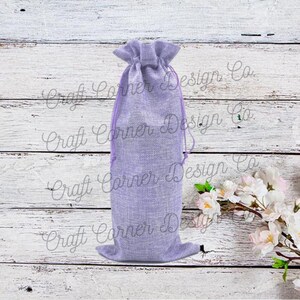 May include: A lavender-colored burlap drawstring bag with a gathered top. The bag is sitting on a white wooden surface.