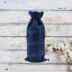 May include: A navy blue burlap bottle bag with a drawstring closure. The bag is sitting on a white wooden surface.