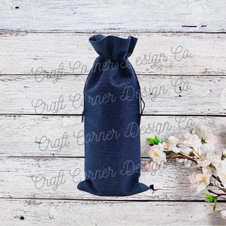 May include: A navy blue burlap bottle bag with a drawstring closure. The bag is sitting on a white wooden surface.