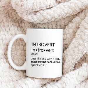 May include: White ceramic coffee mug with black text that reads "INTROVERT in.tro.vert noun Just like you with a little Leave me the f*ck alone sprinkled in."