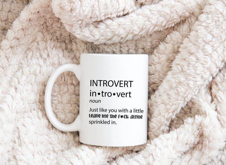 May include: White ceramic coffee mug with black text that reads "INTROVERT in.tro.vert noun Just like you with a little Leave me the f*ck alone sprinkled in."