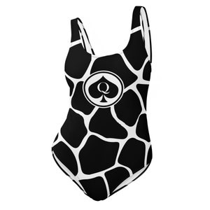May include: Black and white swimsuit with a giraffe print and a black spade with a queen symbol in a circle on the front.