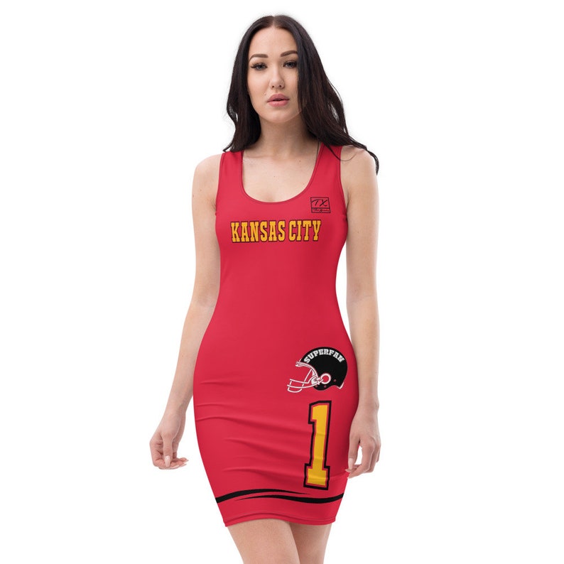 Op de afbeelding: Rode mouwloze jurk met een zwart en geel ontwerp. De jurk heeft de tekst "KANSAS CITY" en het nummer "1" met een voetbalhelm-afbeelding. De tekst "SUPERFAN" staat op de helm.