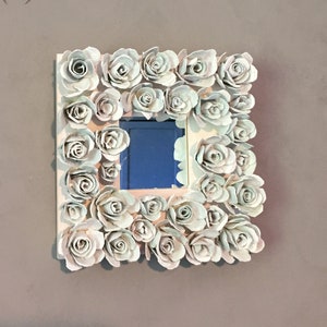 Espejo de pared cuadrado con decoración de flores en relieve.