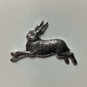 May include: A silver-coloured hare figurine in a running pose. The hare is detailed with fur and has a long tail.