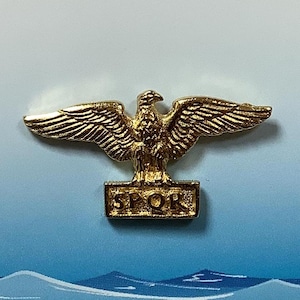 May include: A gold-coloured eagle with outstretched wings standing on a rectangular base with the inscription "SPQR".