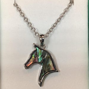 May include: A silver chain necklace with a horse head pendant made of iridescent abalone shell.