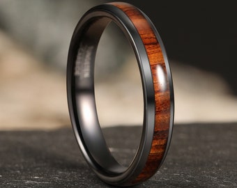 May include: A black tungsten carbide ring with a brown wood inlay. The ring has a polished finish and a beveled edge.
