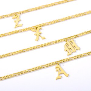 May include: Three gold chains with different letter charms. The charms are in an old English font. The letters are "L", "F", "M", and "A".