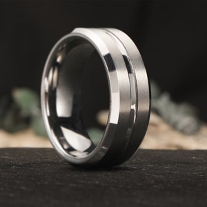 Op de afbeelding: Een zilveren ring van wolfraamcarbide met een afgeschuinde rand en twee gepolijste groeven.