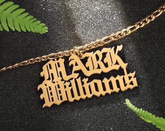 May include: Gold chain necklace with a pendant that says "MARK WILLIAMS" in a gothic font.