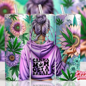 以下が含まれることがあります： 紫とティールのタンブラー。花と大麻の葉のデザイン。紫色のパーカーを着た女性が描かれており、「Canna Mom Get a Break」の文字が書かれています。デザインにはヒマワリと大麻の葉が含まれています。
